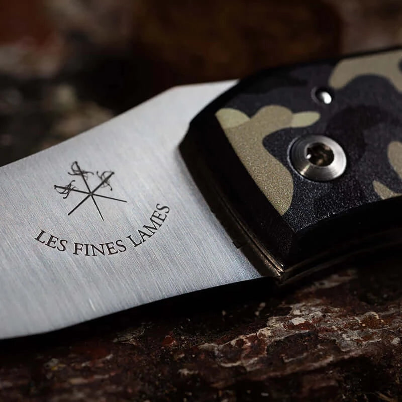 Close-up of Le PETIT Camo Desert knife with desert camouflage handle on a dark surface