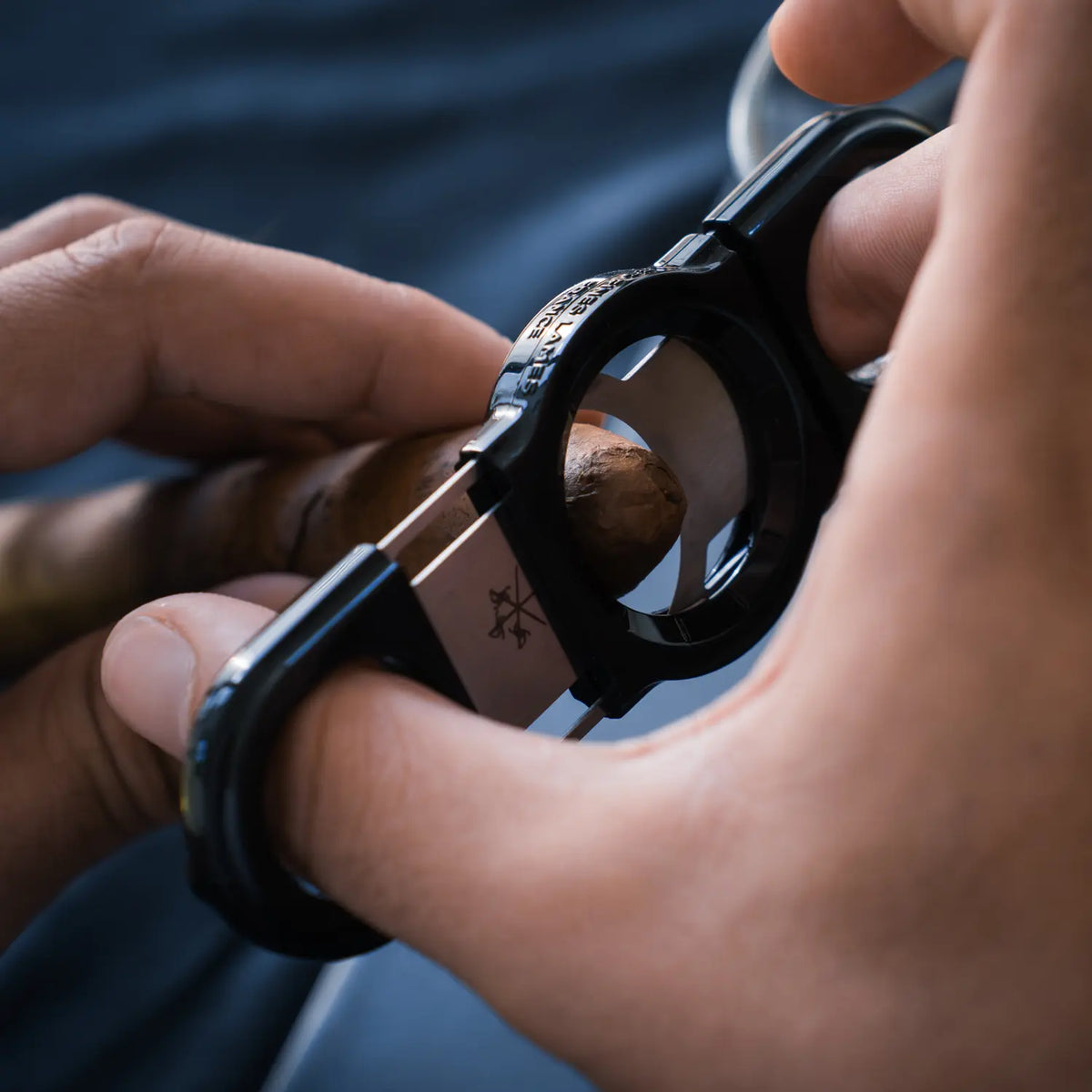La Guillotine Rotor by LES FINES LAMES, a black stainless steel guillotine cigar cutter held in hand