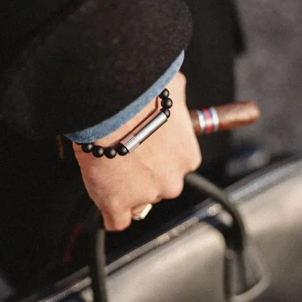 Onyx Matte Punch Bracelet worn on the wrist while carrying luggage and a cigar