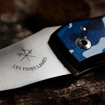 Close-up of Le PETIT Camo Navy knife with blue camouflage handle on a dark surface
