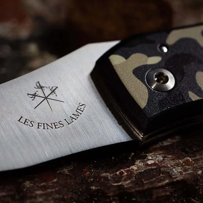 Close-up of Le PETIT Camo Desert knife with desert camouflage handle on a dark surface